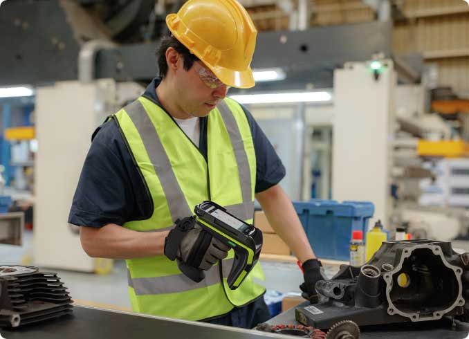 A man in a hardhat scanning a piece of equipment
