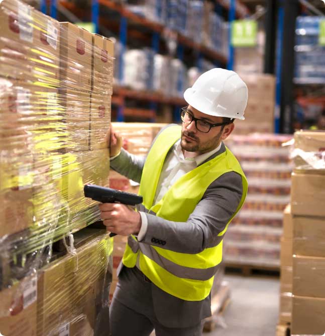 A man scanning a pallet of stock with a barcode scanner