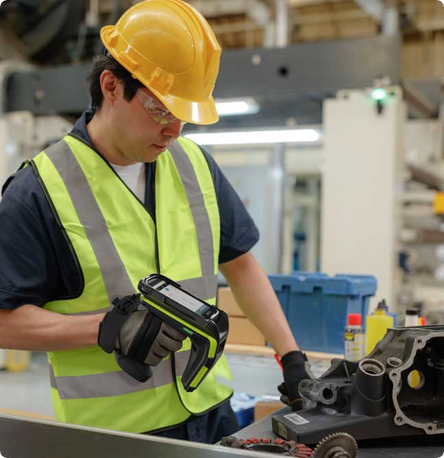 A man wearing a hardhat scanning a piece of equipment