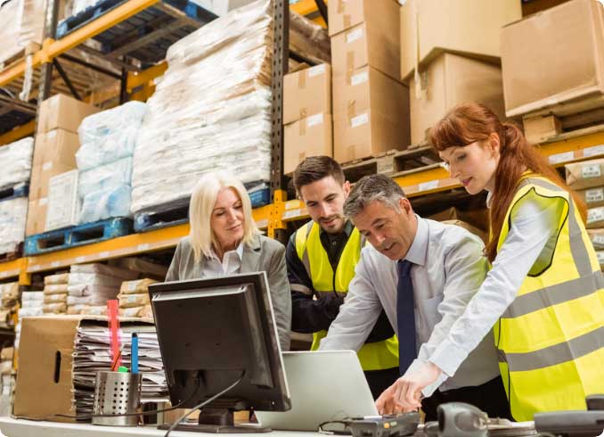 A group of individuals discussing in a warehouse over a computer